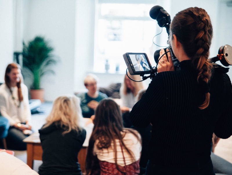 A young lady filming a group of women using professional TV equipment