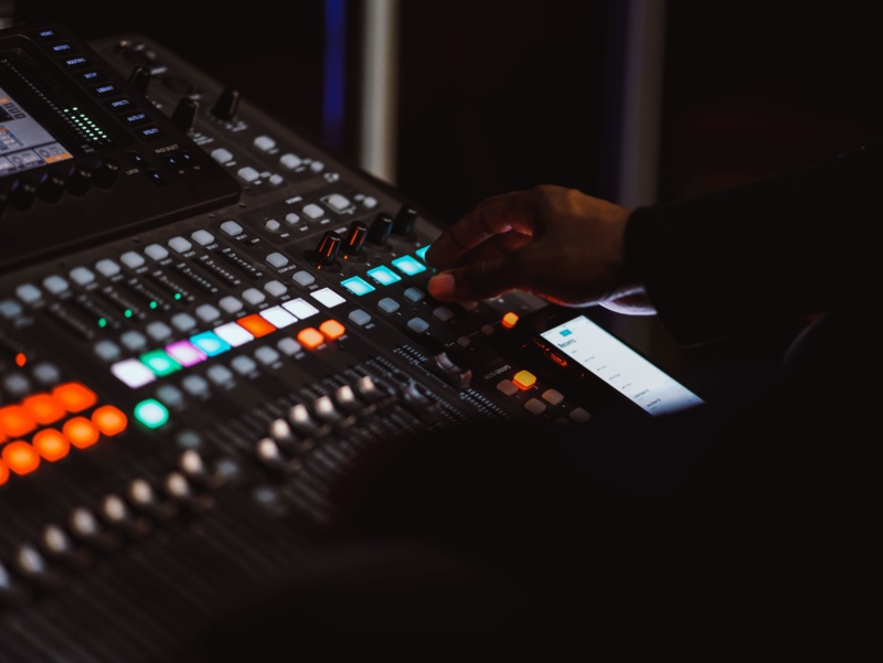 A close-up of a man using a television control and mixing desk